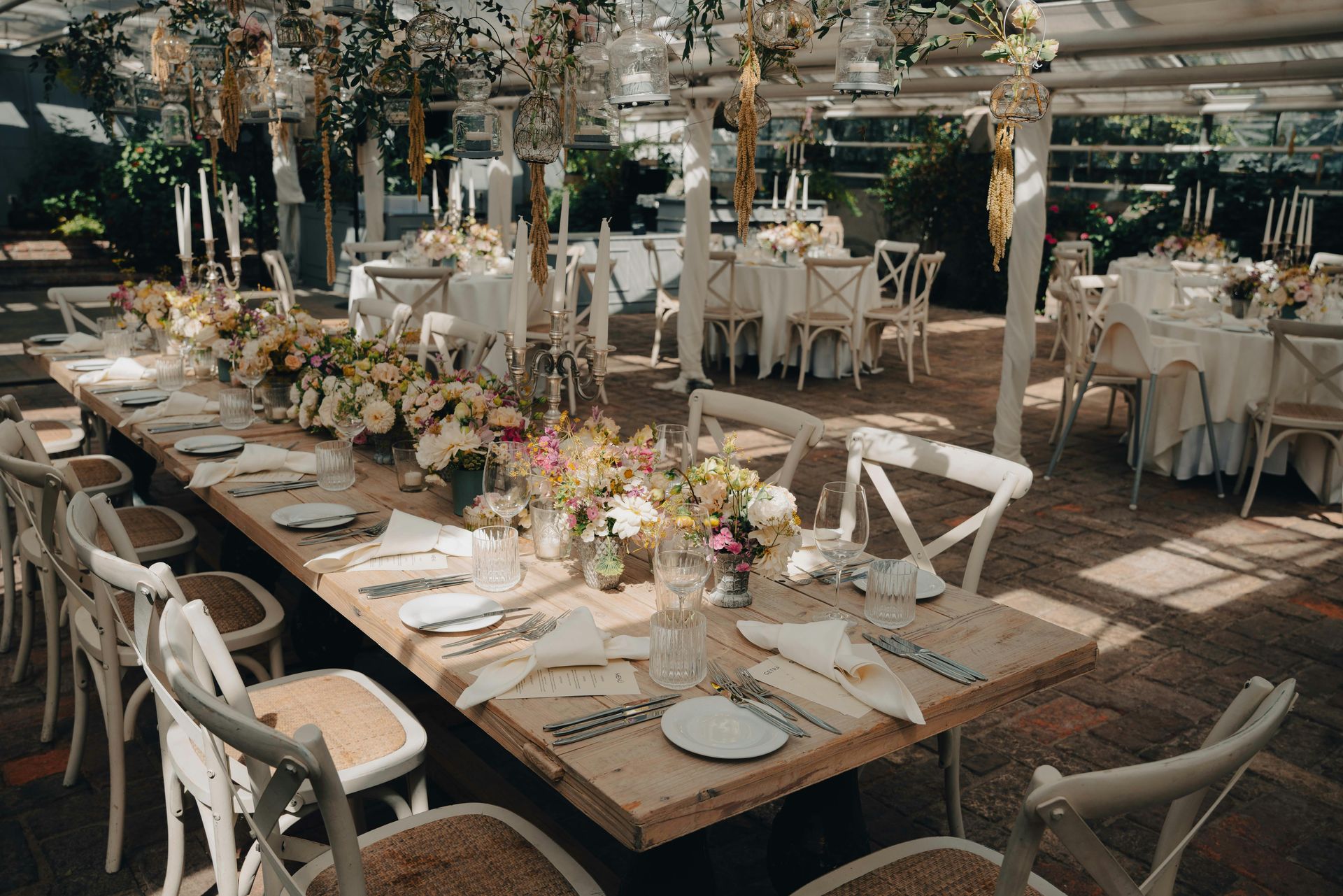 Festlich gedeckte Hochzeitstafel mit ausreichend Platz zwischen Tischen und Stühlen in einem eleganten Hochzeitszelt